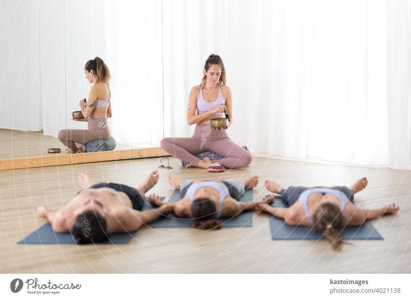 Erholsames Yoga. Gruppe von jungen, sportlichen, attraktiven Menschen im Yoga-Studio, liegend und entspannend auf Yogamatten während Restorative Yoga-Sitzung. Gesunder aktiver Lebensstil.