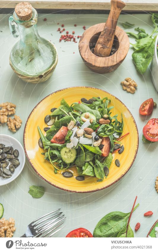 Gesunder grüner veganer Salat mit Nüssen auf gelbem Teller. Ansicht von oben. Vegetarisches Mittagessen Hintergrund Konzept Küche lecker Entzug Diät Speise