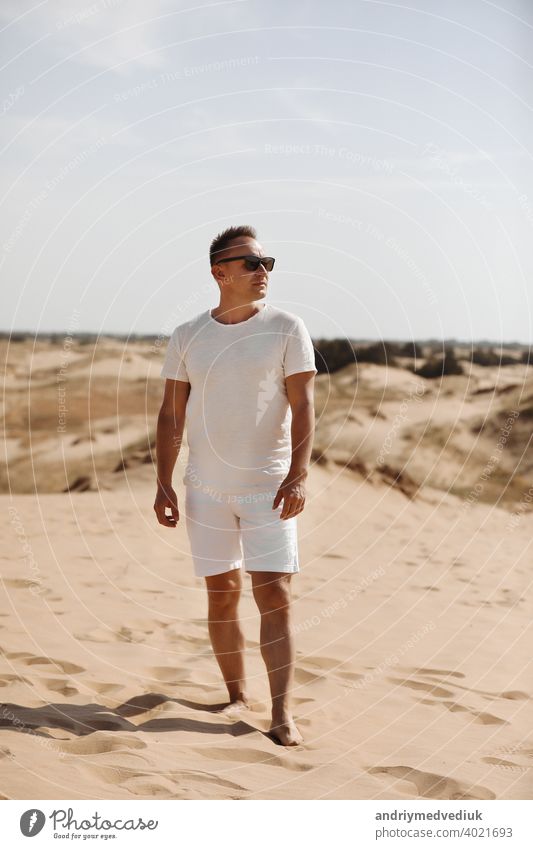 Junge gut aussehende Mann in leichter Kleidung und Sonnenbrille in der Wüste. Konzept der Freiheit Entspannung. Platz für Text oder Werbung jung gutaussehend