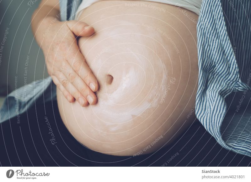 Schwangere Frau, die ihren Bauch eincremt, um Dehnungsstreifen zu vermeiden schwanger Schwangerschaft Sahne Haut Markierungen Lotion Pflege weiß Körper