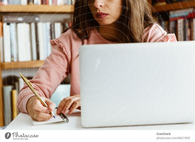 Junge Frau bei der Arbeit am weißen Marmorschreibtisch in ihrem Haus. jung arbeiten Schreibtisch Person Hand Tisch Notizen Murmel Bibliothek hölzern