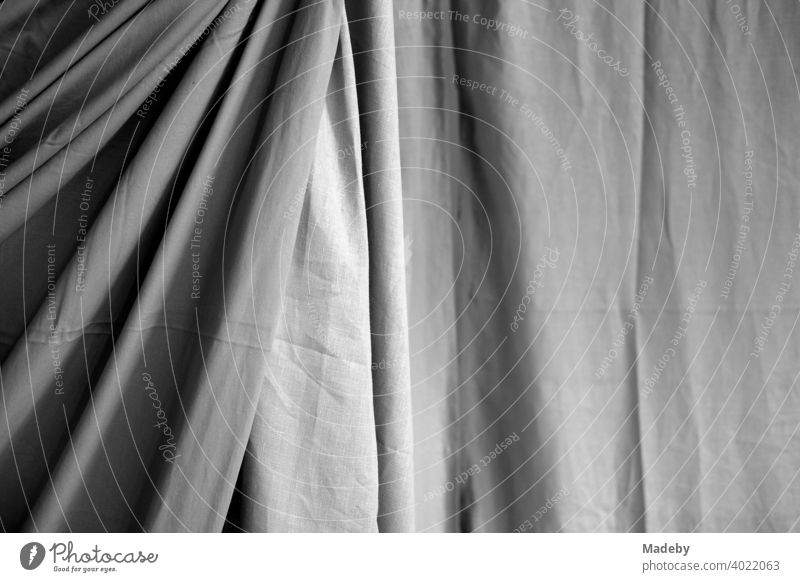 Großer Vorhang aus Stoff mit Falten und Schattenwurf in einer Designerwohnung in Rudersau bei Rottenbuch im Kreis Weilheim-Schongau in Oberbayern, fotografiert in klassischem Schwarzweiß