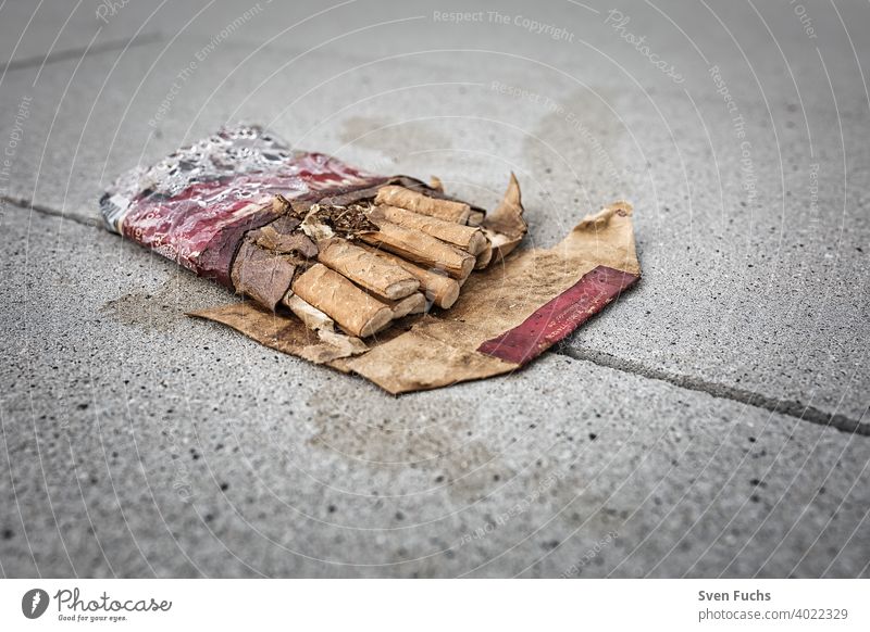 Eine zerdrückte Zigarettenschachtel mit Zigaretten liegt auf dem Betonboden zigaretten zigarettenschachtel rauchen nichtrauchen zerknüllt gesundheit