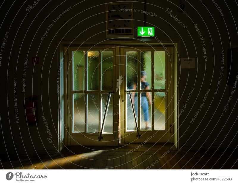 Warten vor der Doppeltür im Sonnenlicht Tür Frau hinten DDR Glastür retro Notausgang Zeichen Durchgang stehen durchsichtig Körperhaltung Stil Ostalgie Treptow