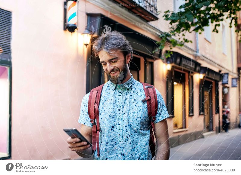 Mann schaut auf der Straße auf sein Telefon. Erwachsener Glück Lifestyle Kaukasier Fröhlichkeit Lächeln Spaß Liebe Freude Freizeit heiter Lachen Termin & Datum