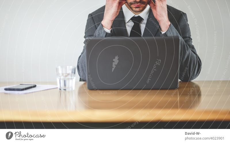 Mann im Anzug am Laptop Arbeitsplatz laptop Notebook überlastet angestrengt Kopfschmerzen konzentriert Schreibtisch Business businessmann Homeoffice