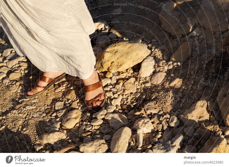 Eine Frau, Mädchen mit weißem Rock läuft mit bequemen Sandalen über einen steinigen Weg Schuhe fuesse weg finden Beine Fuß Mensch Erwachsene Damenschuhe feminin