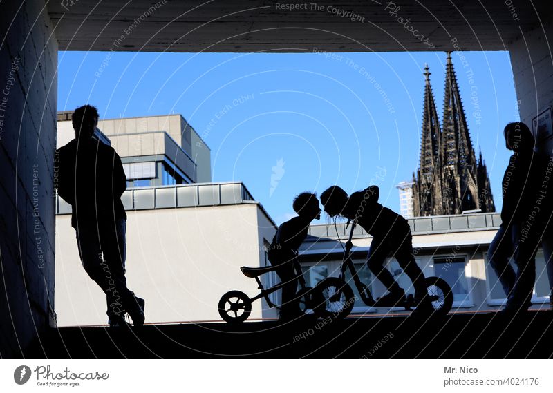 kopf an kopf Hinterhof Kölner Dom Silhouette Wahrzeichen Gebäude Stadt Tunnel Fahrrad Fahrradfahren Bauwerk Wolkenloser Himmel Kindheit Konflikt & Streit