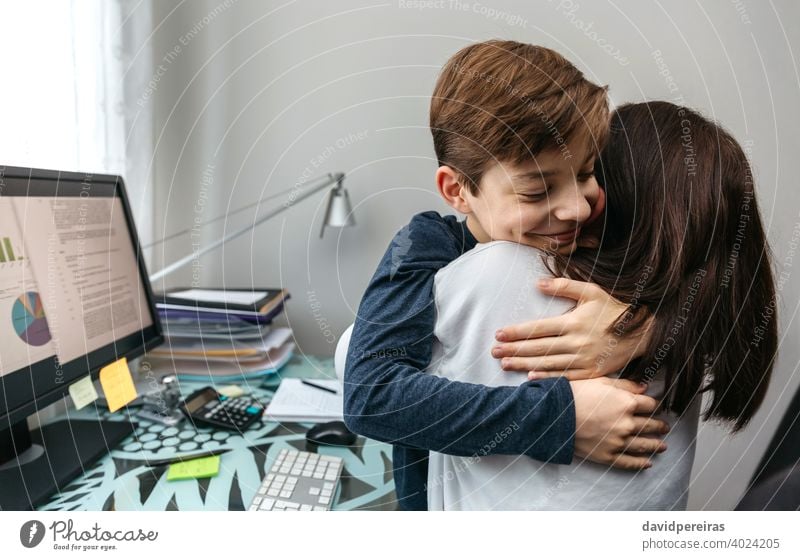 Mutter und Sohn umarmen sich, während sie Telearbeit macht Arbeit Familie Schlichtung umarmend Liebe Textfreiraum Glück Lächeln Coronavirus Sperrung Teenager