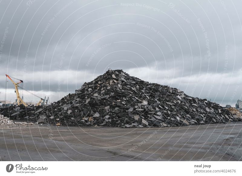 Geröllhaufen auf einer Industriebrache, den eine einzelne Möwe als Aussichtspunkt nutzt Brachland Hafen Hafenkran Hügel Haufen Steine Asphalt Schutt grau