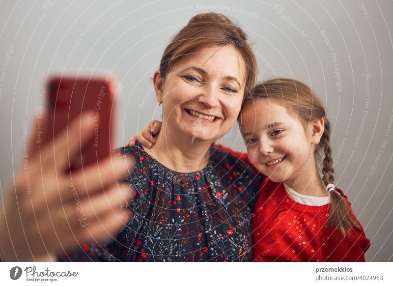 Mutter mit ihrer kleinen Tochter machen Videoanruf mit Handy. Frau und kleines Mädchen im Gespräch mit Verwandten. Fröhliche Familie mit Spaß nehmen selfie Foto mit Smartphone