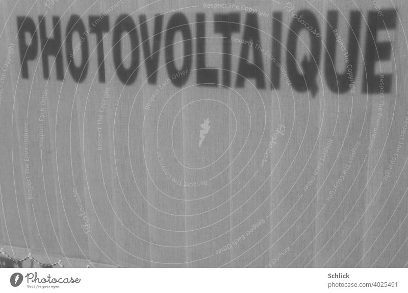Schatten der französischen Aufschrift "PHOTOVOLTAIQUE" eines Schaufensters fällt auf eine geschlossene Innenjalousie mit viel Textfreiraum unten Schlagschatten