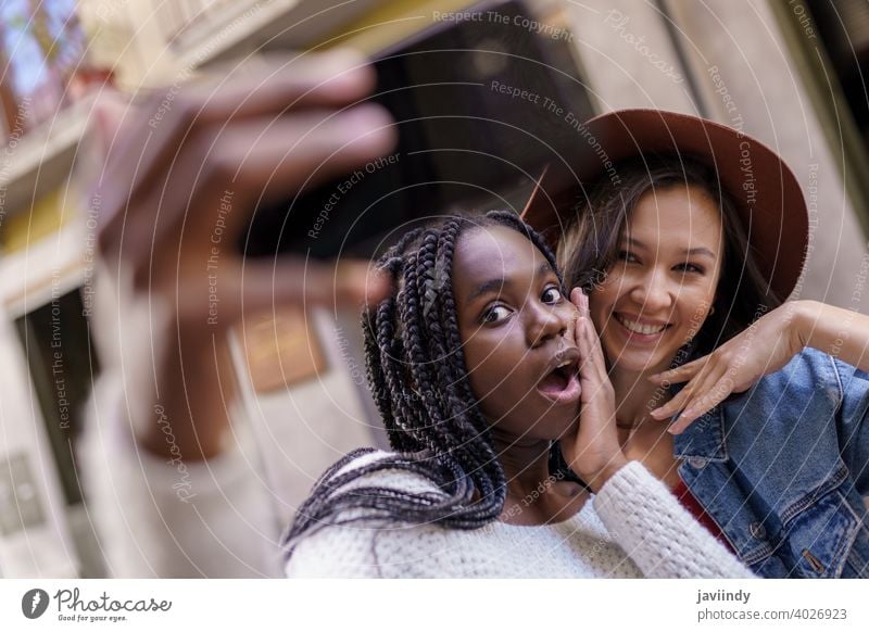 Zwei schöne multiethnische Frauen, die Selbstgefälligkeit und Grimassen schneiden Selfie Smartphone Lifestyle jung Mädchen Lächeln Straße Glück lässig urban