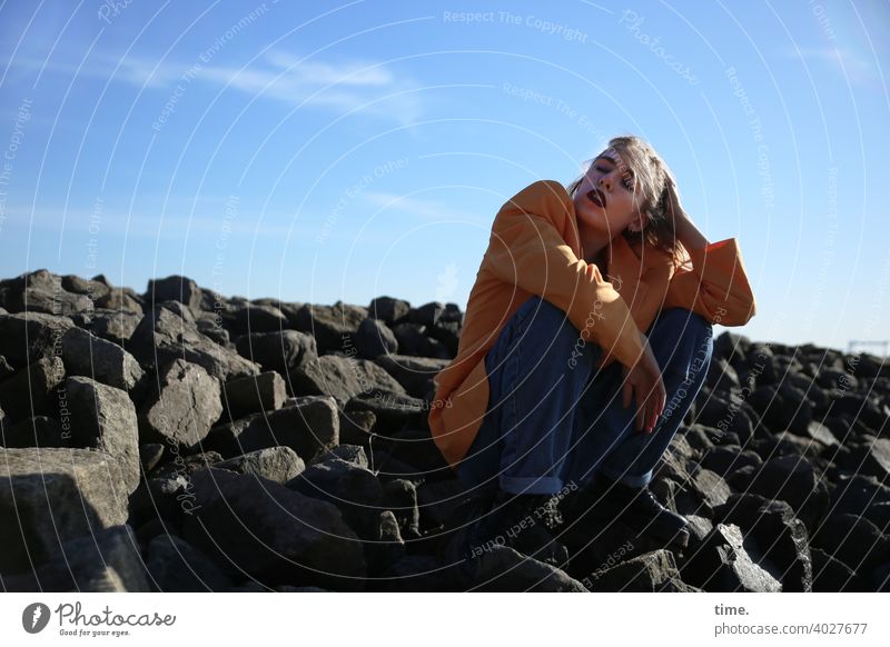 Lara frau jacke wellenbrecher steine himmel sitzen hand schutz sonnig jeans aufstützen abstützen wolken schatten