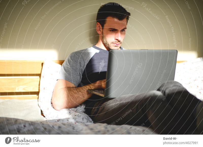 Mann arbeitet zu Hause im Bett am Laptop chillen arbeiten bequem Homeoffice lässig