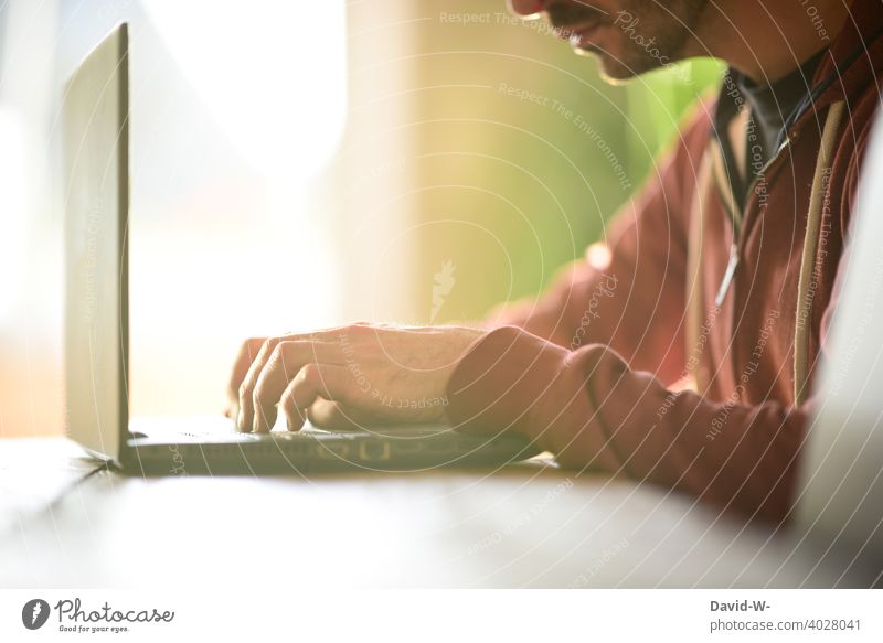 Student am Laptop Distanzunterricht studieren zu Hause Online-Shopping online Hände Tastatur tippen Internet Sonnenlicht