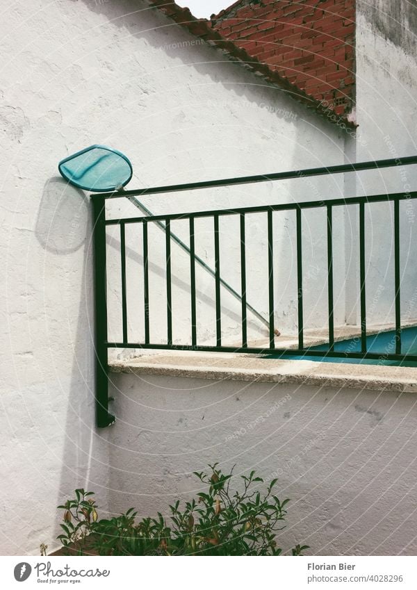 Pool-Kescher lehnt neben einem Schwimmbecken im Hinterhof an einem Eisengeländer Schwimmbad Mauer Ziegel Geländer Wand Menschenleer Haus Fassade Hof