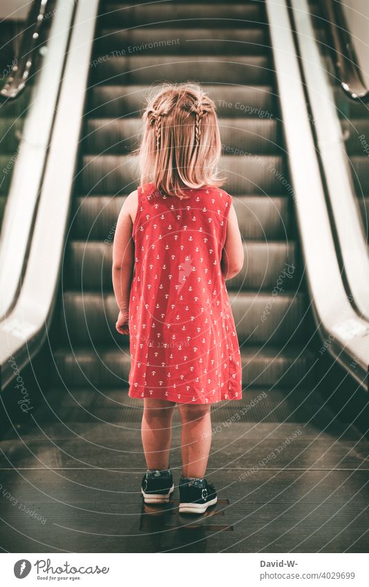 Mädchen in Gedanken steht vor einer Rolltreppe Kleid einkaufen Einkaufszentrum alleine Kind gefahr verloren ängstlich Kaufhaus Angst