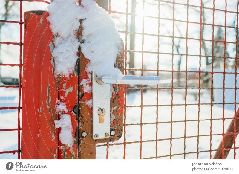 roter Zaun aus Metall mit Tor im Winter mit Schnee Eingang Gitter Gitterzaun Griff Grundstück Grundstückgrenze Schloss Sonnenschein Türgriff öffnen Sicherheit
