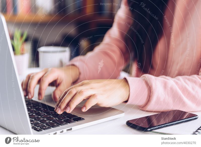 Junge Frau arbeitet am Laptop auf weißem Marmor Schreibtisch in ihrem Haus. jung arbeiten Person Arbeit Hand Tisch Murmel Bibliothek hölzern Kaffee Becher