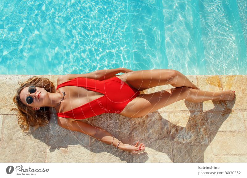 Junge Frau im roten Badeanzug entspannt in der Nähe eines Pools tropisch Wasser einteilig Textfreiraum Boho legen Draufsicht Sommer jung Kaukasier Mode allein