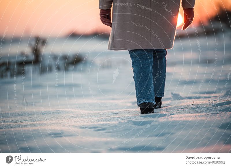 Anonyme Person geht auf verschneitem Feld Winter Schnee Spaziergang Bein Stiefel Fußspur Sonnenuntergang allein Natur Saison Sohle frisch Landschaft kalt Wetter