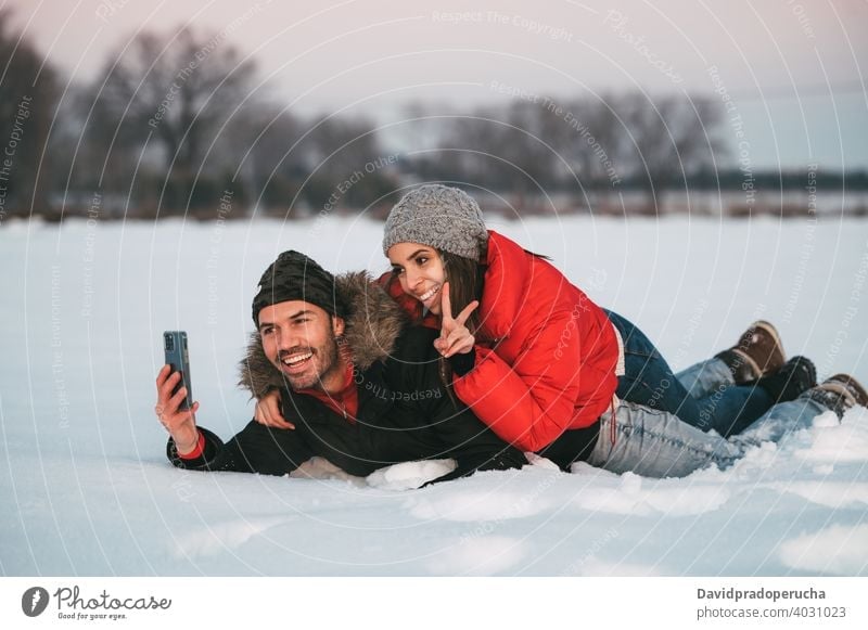 Lachendes Paar nimmt Selfie auf Schnee Winter Spaß haben heiter Landschaft Liebe Zusammensein Smartphone Freude Feld romantisch Partnerschaft Zuneigung