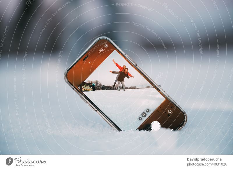 Paar, das Spaß hat und Fotos im verschneiten Feld macht Selfie Smartphone Winter Schnee Huckepack Spaß haben Telefon Bildschirm Zusammensein romantisch