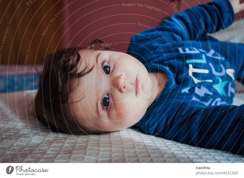 Kleines Baby in Blau liegt auf einem Bett Säuglingsalter niedlich lieblich Mädchen Schlafzimmer heimwärts Familie bezaubernd blau Pyjama spielerisch Gesicht