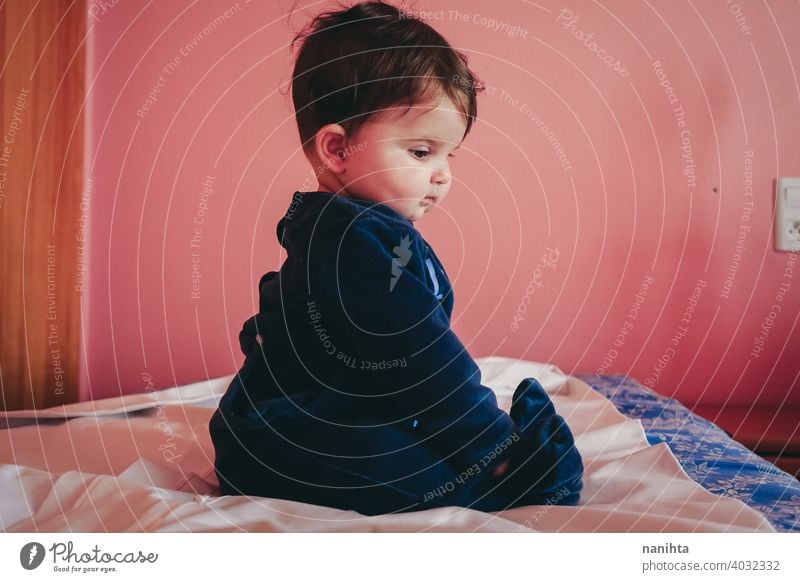 Kleines Baby sitzt auf einem Bett in einem rosa Zimmer sitzen Sitzen Säuglingsalter niedlich bezaubernd lieblich Pyjama blau Europäer Kaukasier heimwärts