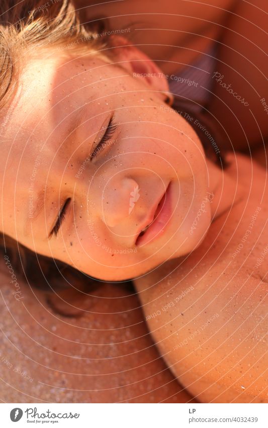Schönes Kind mit geschlossenen Augen und sandigem Gesicht geschlossene Augen Vorderansicht Porträt Sonnenstrahlen Kontrast Schatten Licht Textfreiraum unten
