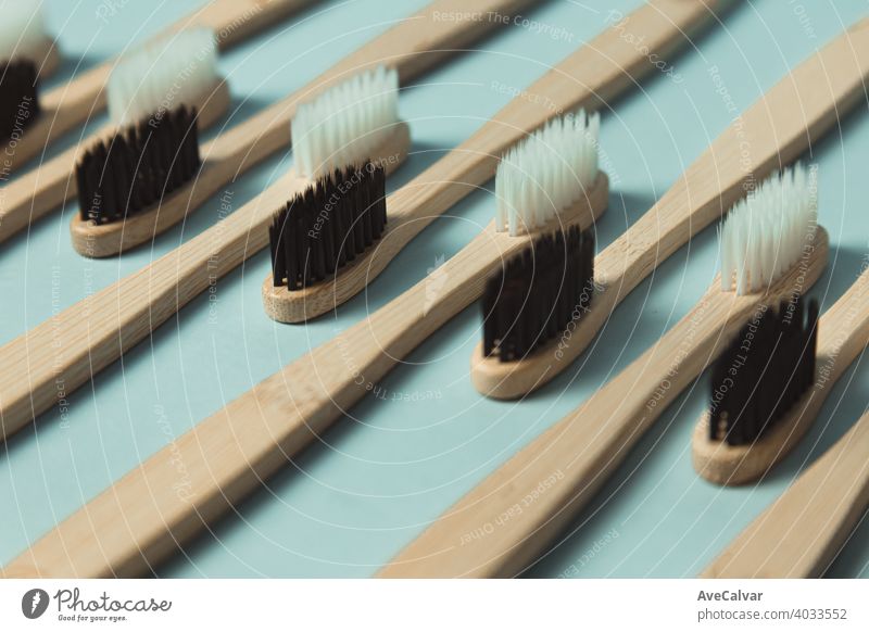 Eine Nahaufnahme von einem minimalistischen und sich wiederholenden Patron einer Menge von Bambus-Zahnbürste über einen klaren blauen Hintergrund gemustert