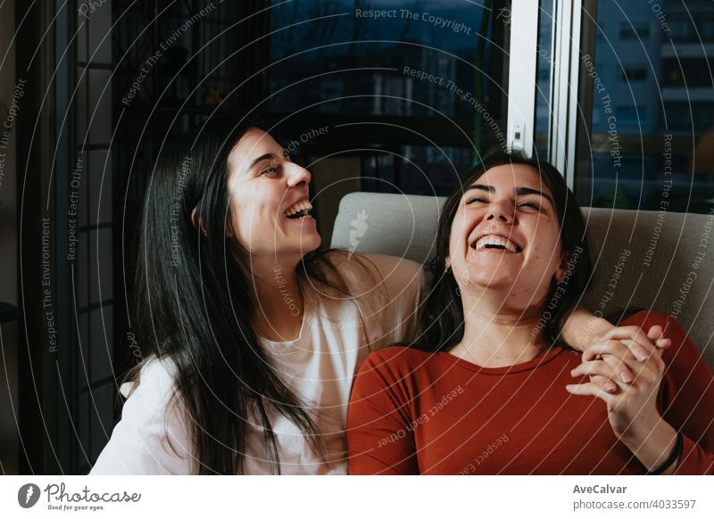 Ein Paar von Frau lachend auf der Couch während einer glücklichen Nacht in der Wohnung der Stadt anhänglich Antwort an Kuscheln umarmend Freunde Mädchen