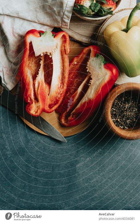 Attrappe eines Kochtisches mit einer halbierten Paprika, einem Messer und einigen Gewürzen Leinwand Essen zubereiten Karotten Altholz horizontal produzieren