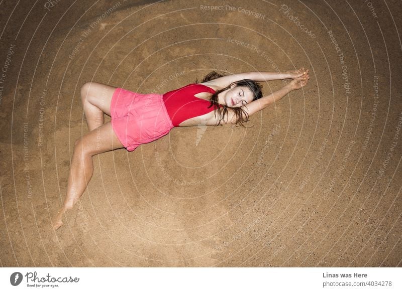 Wunderschöne Brünette Modell Gefühl gemütlich und entspannt auf diesem Hügel von Sand. Gekleidet in rosa Shorts und einem roten Badeanzug, der ihre sexy Kurven nicht verbergen kann. Die Perfektion der wilden Sommernächte.