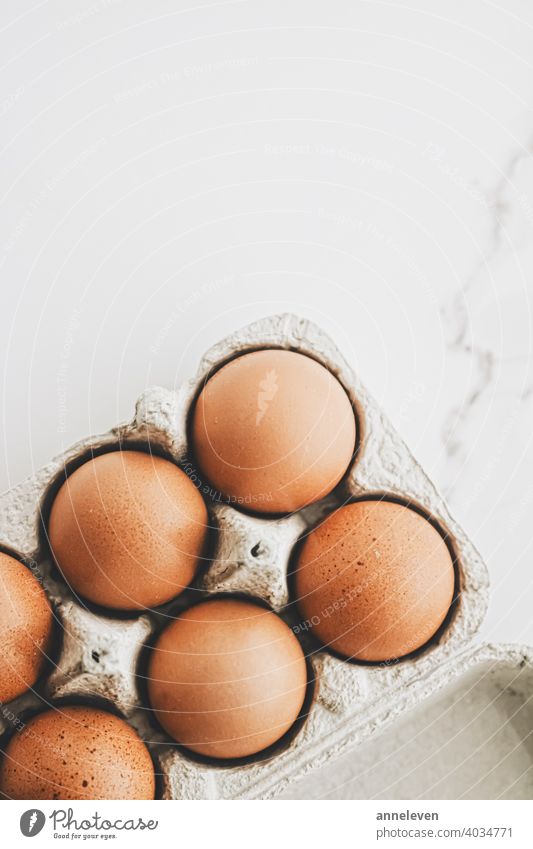 Bio-Eier im Eierkarton auf weißem Marmor-Küchentisch authentisch Kasten Frühstück braun Karton Schachtel Hähnchen filmisch Nahaufnahme Container copyspace