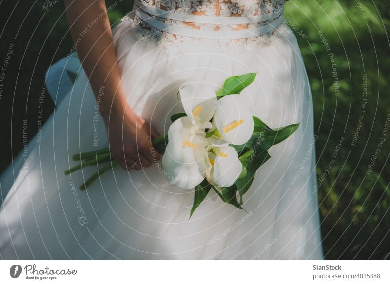 Junge schöne Braut hält einen Blumenstrauß. Hochzeit Kleid weiß Schönheit Frau Mädchen jung hochzeitlich Natur Bäume Feier Liebe Eleganz Hintergrund Glück Farbe