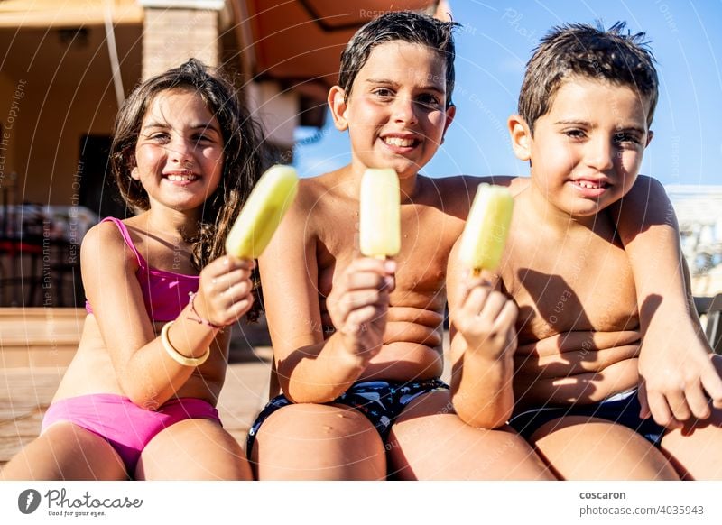 Drei lustige Kinder essen einen Eislutscher Junge Bruder Kaukasier heiter Kindheit Sahne Tochter Tag Latzhose genießen Außenseite Familie Lebensmittel frisch