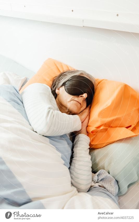 Eine alte Dame schläft mit einer Gesichtsmaske in einem modernen Schlafzimmer Mundschutz Frau Senior Nacht schlafen grauhaarig Morgen Pyjama Großmutter Ausdruck