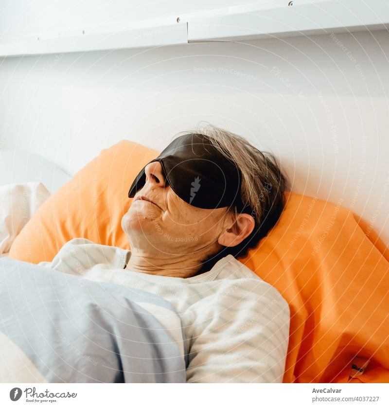Eine alte Dame schläft mit einer Gesichtsmaske in einem modernen Schlafzimmer Mundschutz Frau Senior Nacht schlafen grauhaarig Morgen Pyjama Großmutter Ausdruck