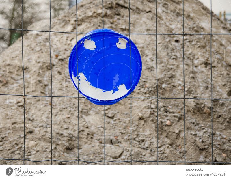 freundlicher Deckel am Drahtzaun Sandhaufen Plastikdeckel Smiley Baustelle befestigt einfach Straßenkunst Kreativität Kreis Inspiration Strukturen & Formen