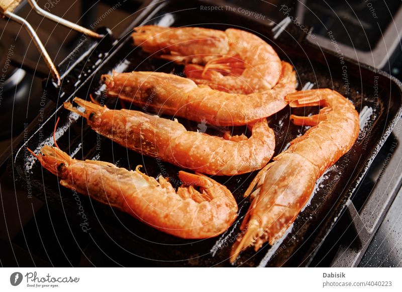 Gegrillte große Garnelen mit Zitrone und Gewürzen in der Grillpfanne Grillrost Meeresfrüchte Lebensmittel rot Hintergrund dunkel schwarz Krebstier MEER Speise