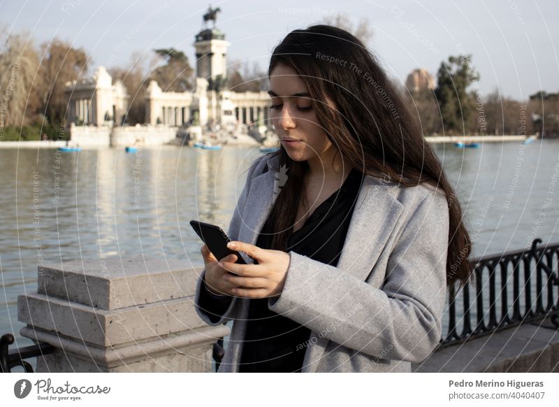 Frau sucht ihr Telefon in einem Park. Spielen Mädchen Hand Beteiligung Anwendung Straße Dame laufen sozial Spaziergang App außerhalb Leben zuschauend