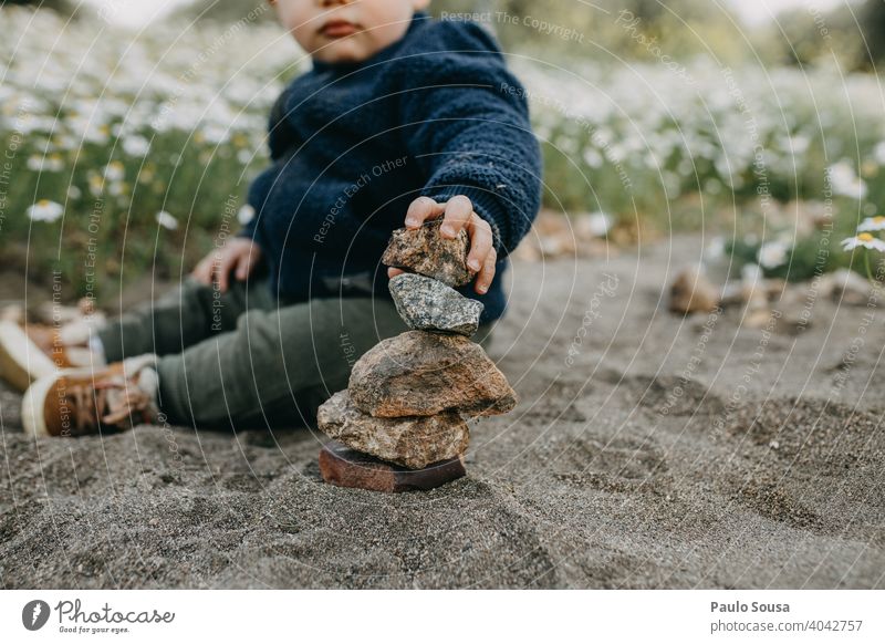 Kind spielt mit Steinen im Freien Kindheit Kaukasier 1-3 Jahre Mittelteil erkunden Felsen Ausgeglichenheit Haufen Außenaufnahme Fröhlichkeit Spielen Tag