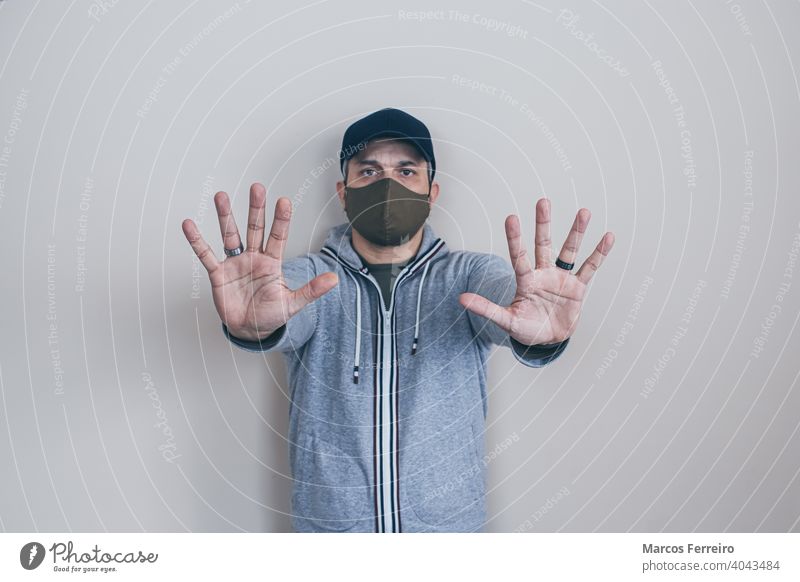 Mann mit Maske stoppt Hände Gesichtsmaske Prävention Kaukasier Ermahnung Sicherheit jung gestikulierend nein Menschen Gefahr Pandemie Seuche Infektion Stehen