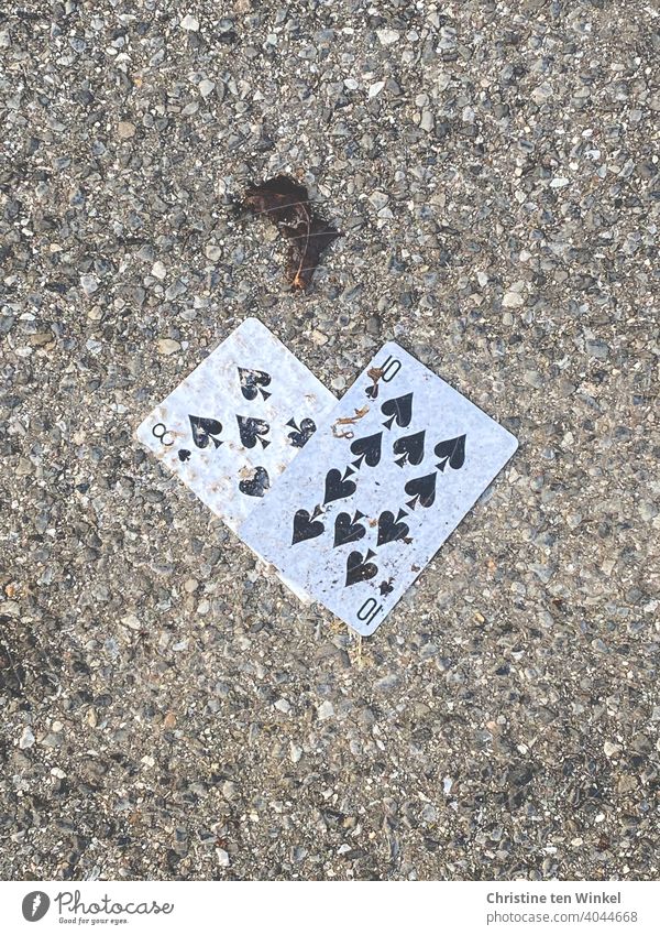 ungesund | Spielsucht...  Zwei verlorene oder weggeworfene schmutzige Spielkarten liegen auf dem grauen Asphalt Boden Straße Wege & Pfade Bürgersteig