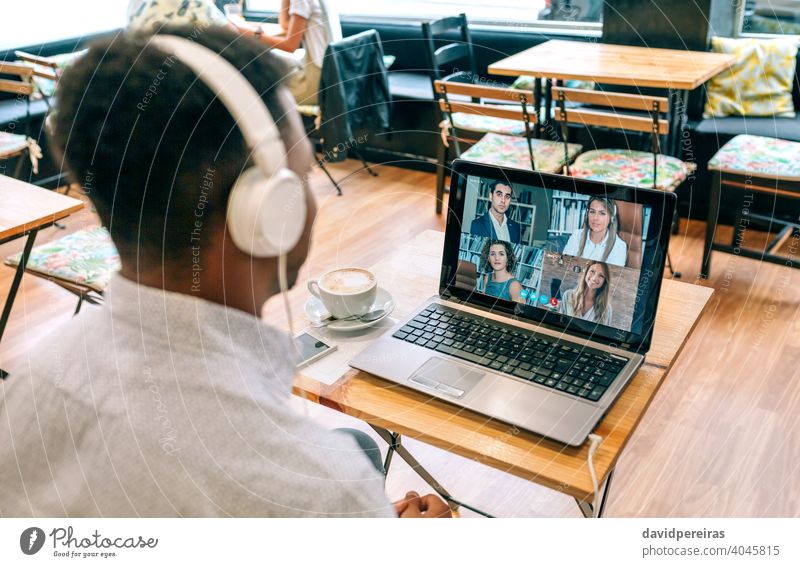 Mann arbeitet per Videokonferenz von einem Café aus unkenntlich Arbeitstreffen soziale Distanzierung Laptop Fernarbeit arbeiten Kaffeehaus Kopfhörer Partner