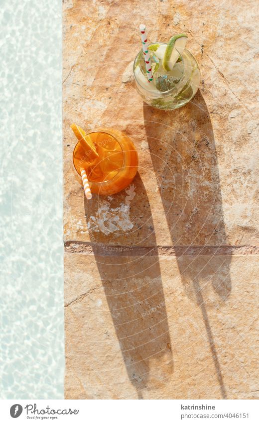 Zwei erfrischende Cocktails in der Nähe eines Swimmingpools Mojito Mocktail orange Minze Kalk Draufsicht niemand Glas Pool Schwimmbad Caipiroska Caipirinha