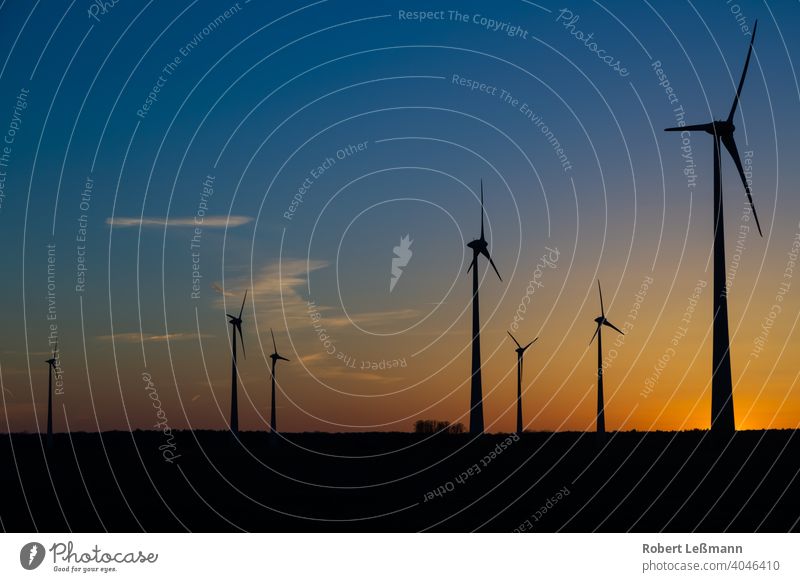 viele Windräder bei Sonnenuntergang stehen auf einem Feld und produzieren Strom windräder ökostrom umweltfreundlich klimaschutz abendrot sonnenuntergang