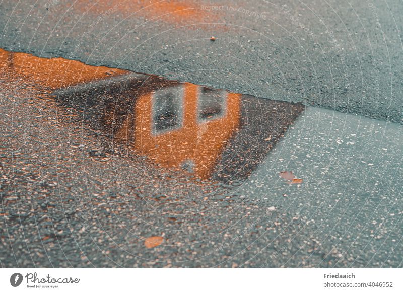 Spiegelung eines Hauses in der Pfütze auf dem Asphalt Spiegelung im Wasser Straße Pfützenspiegelung nass Regenspaziergang Außenaufnahme Farbfoto Menschenleer